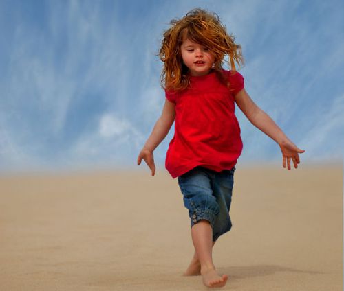 Девочка идет по песку босиком