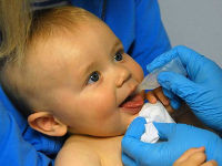 Ребенку в рот капают вакцину